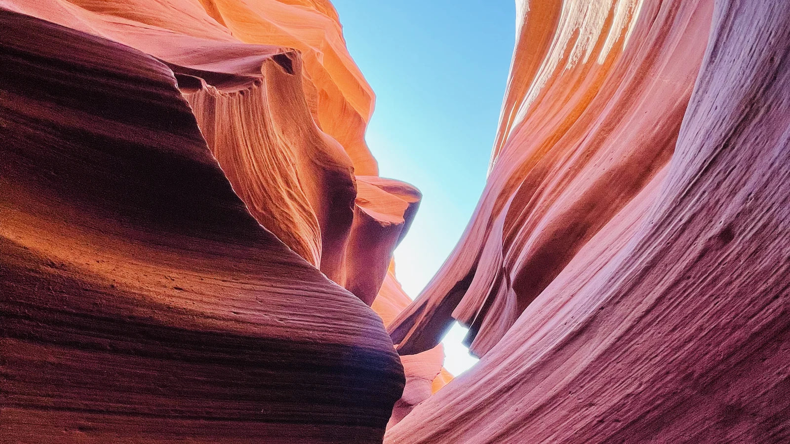Sunlit sandstone curves in a narrow slot canyon, layered copper and amber, photographed by the founder in northern Arizona
