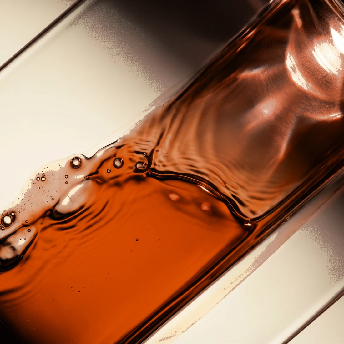 Macro of the dark reddish-amber Radiance oil-serum in warm light.